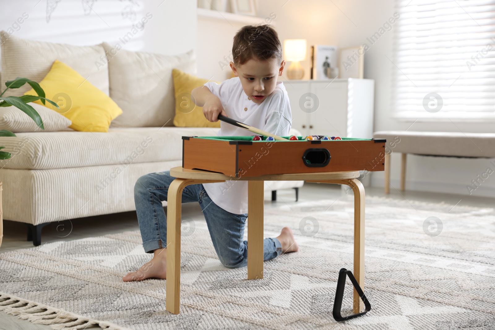 Photo of Cute little boy playing billiards at home