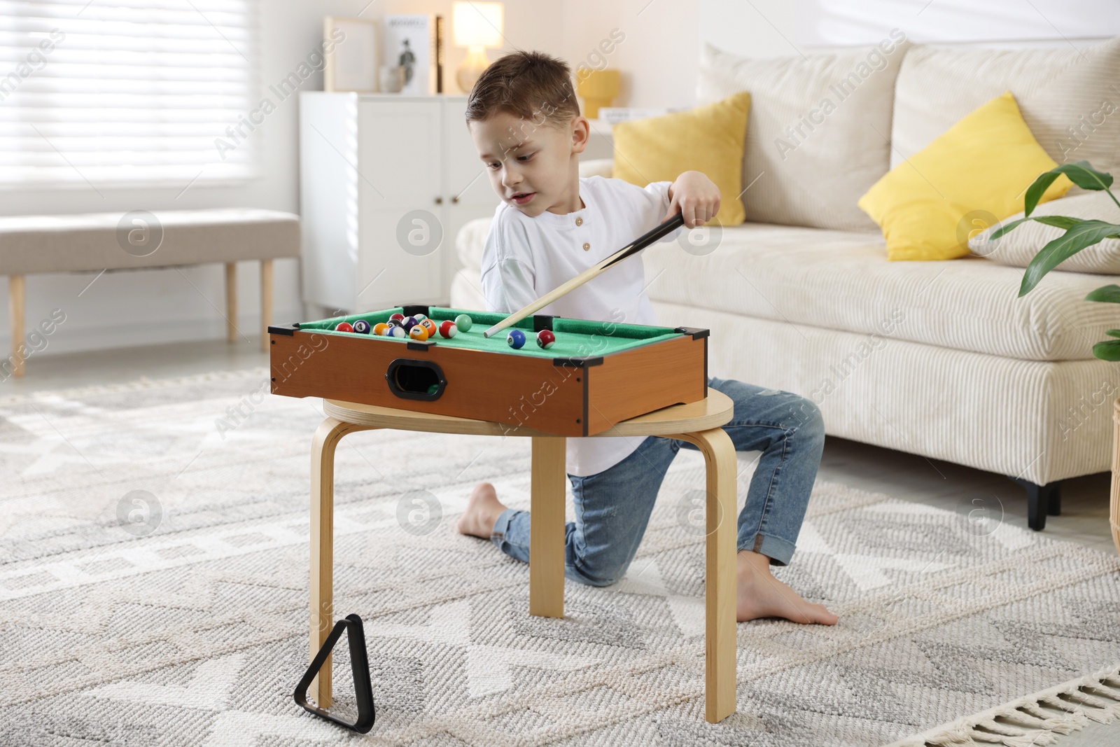 Photo of Cute little boy playing billiards at home