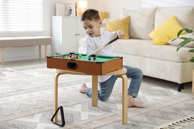 Photo of Cute little boy playing billiards at home