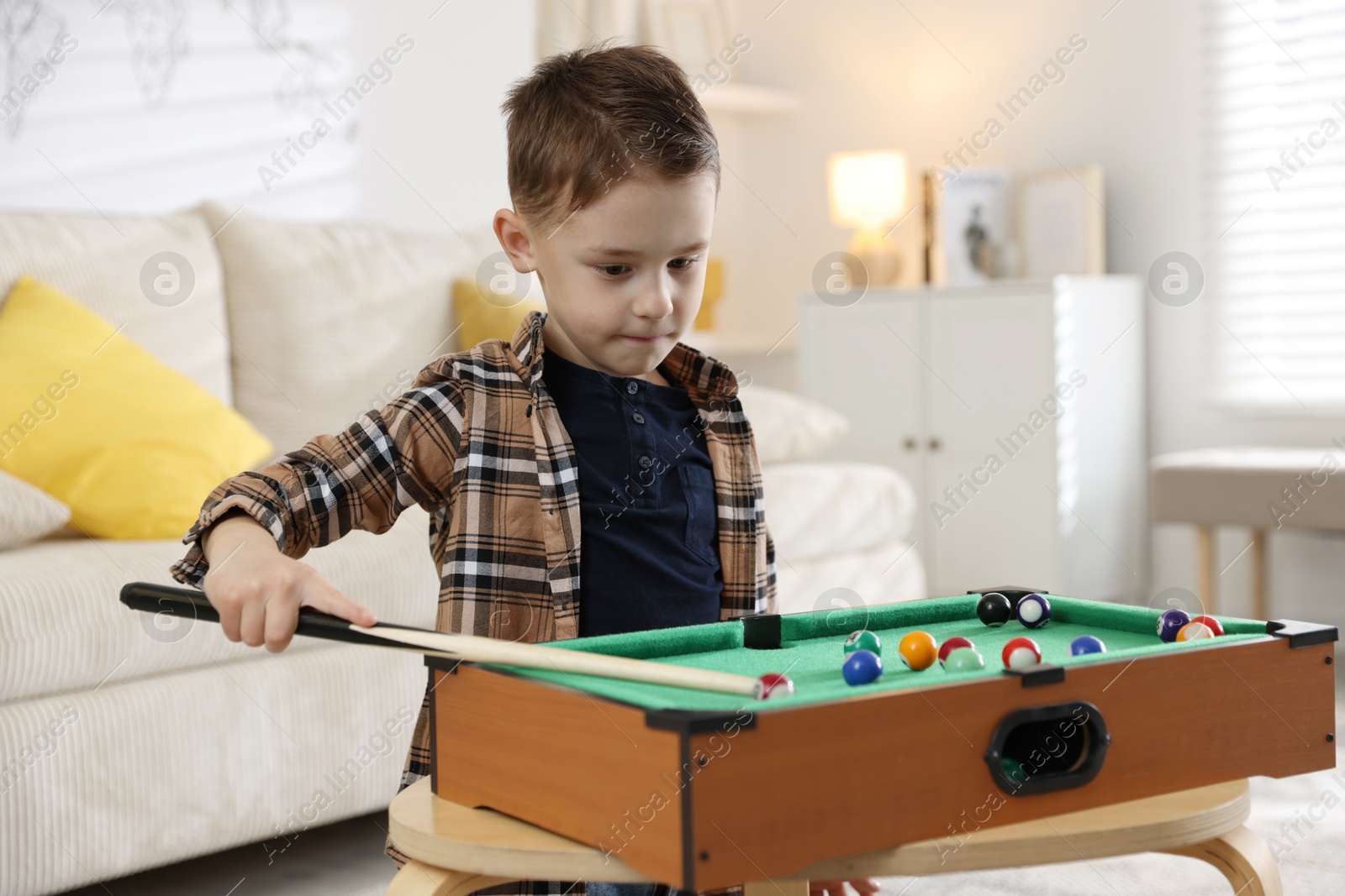 Photo of Cute little boy playing billiards at home