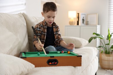 Cute little boy playing billiards at home