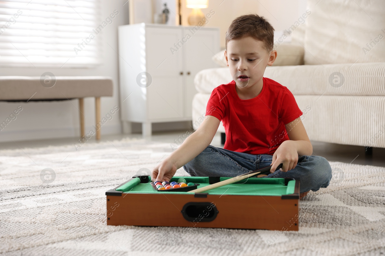 Photo of Cute little boy playing billiards at home