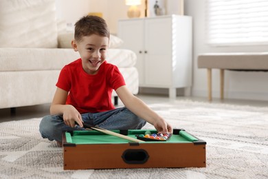 Cute little boy playing billiards at home