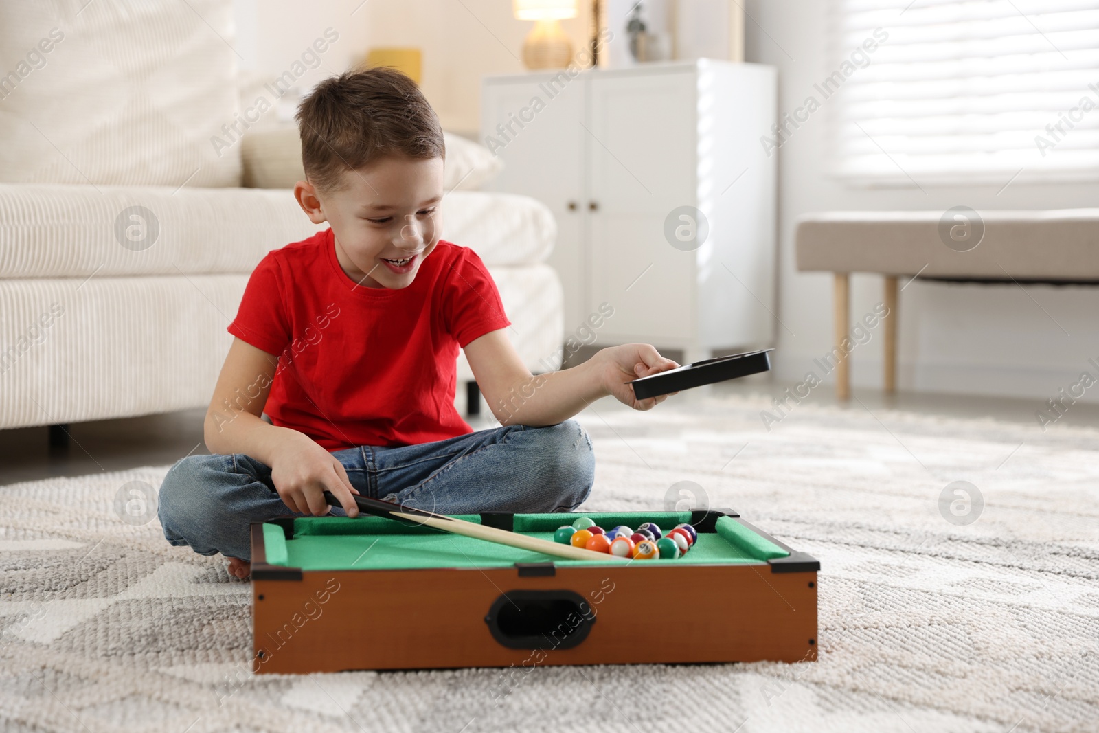 Photo of Cute little boy playing billiards at home