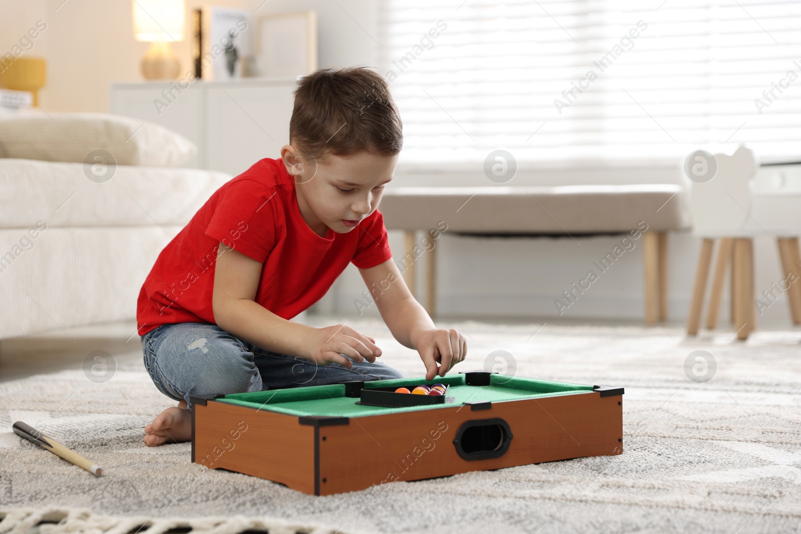 Photo of Cute little boy playing billiards at home