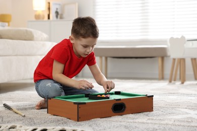 Cute little boy playing billiards at home