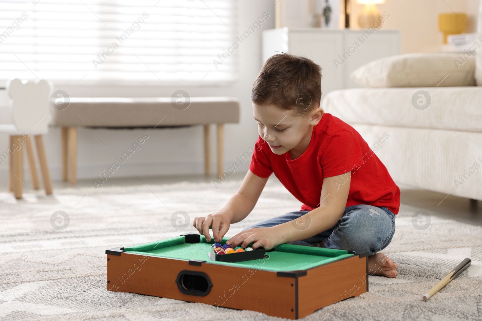 Photo of Cute little boy playing billiards at home