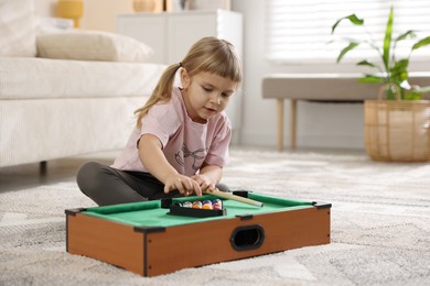 Cute little girl playing billiards at home