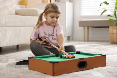 Cute little girl playing billiards at home