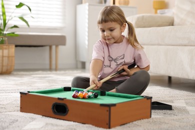 Cute little girl playing billiards at home