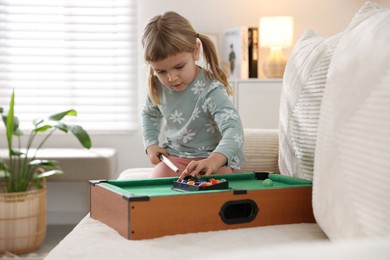 Photo of Cute little girl playing billiards at home