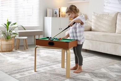 Cute little girl playing billiards at home