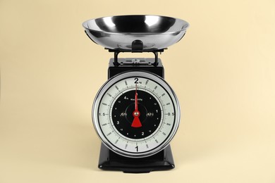 Photo of Mechanical kitchen scale with bowl on beige background