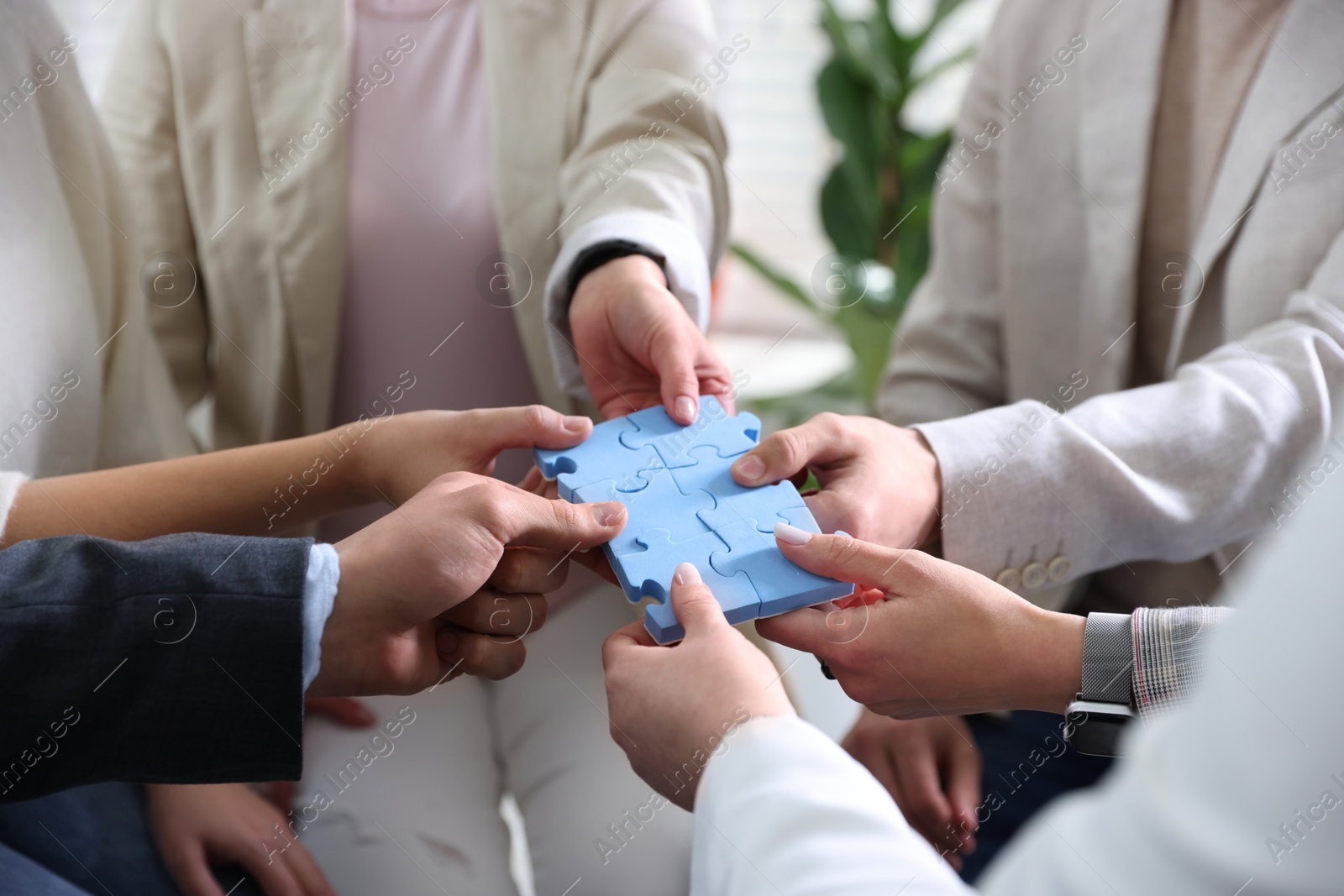 Photo of Unity concept. People putting puzzle pieces together indoors, closeup