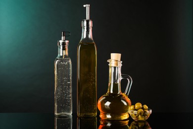 Photo of Salad dressings and olives on mirror surface against black background