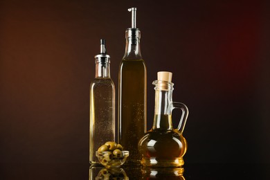 Photo of Salad dressings and olives on mirror surface against dark background