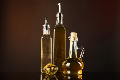 Photo of Salad dressings and olives on mirror surface against dark background