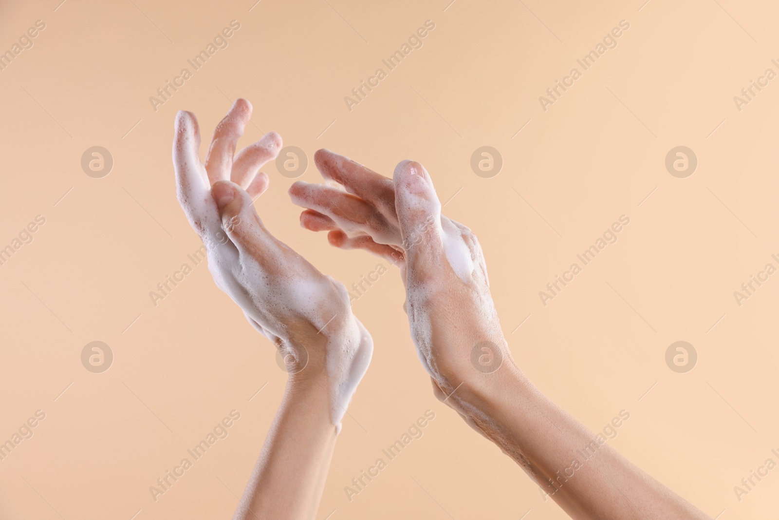 Photo of Woman washing hands with foaming soap on beige background, closeup. Hygiene