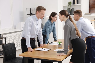 Photo of Competition concept. Group of businesspeople looking and examining each other at table in office