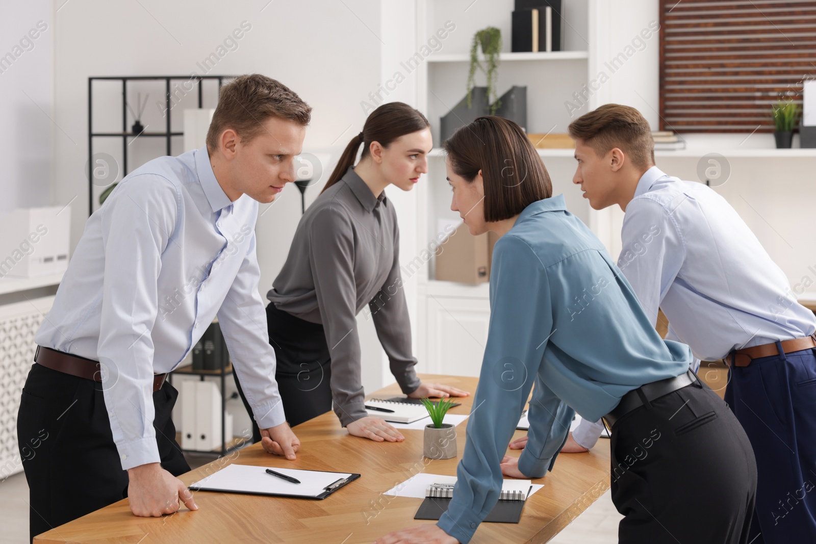 Photo of Competition concept. Group of businesspeople looking and examining each other at table in office