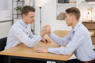 Competition concept. Businessmen arm wrestling at table in office