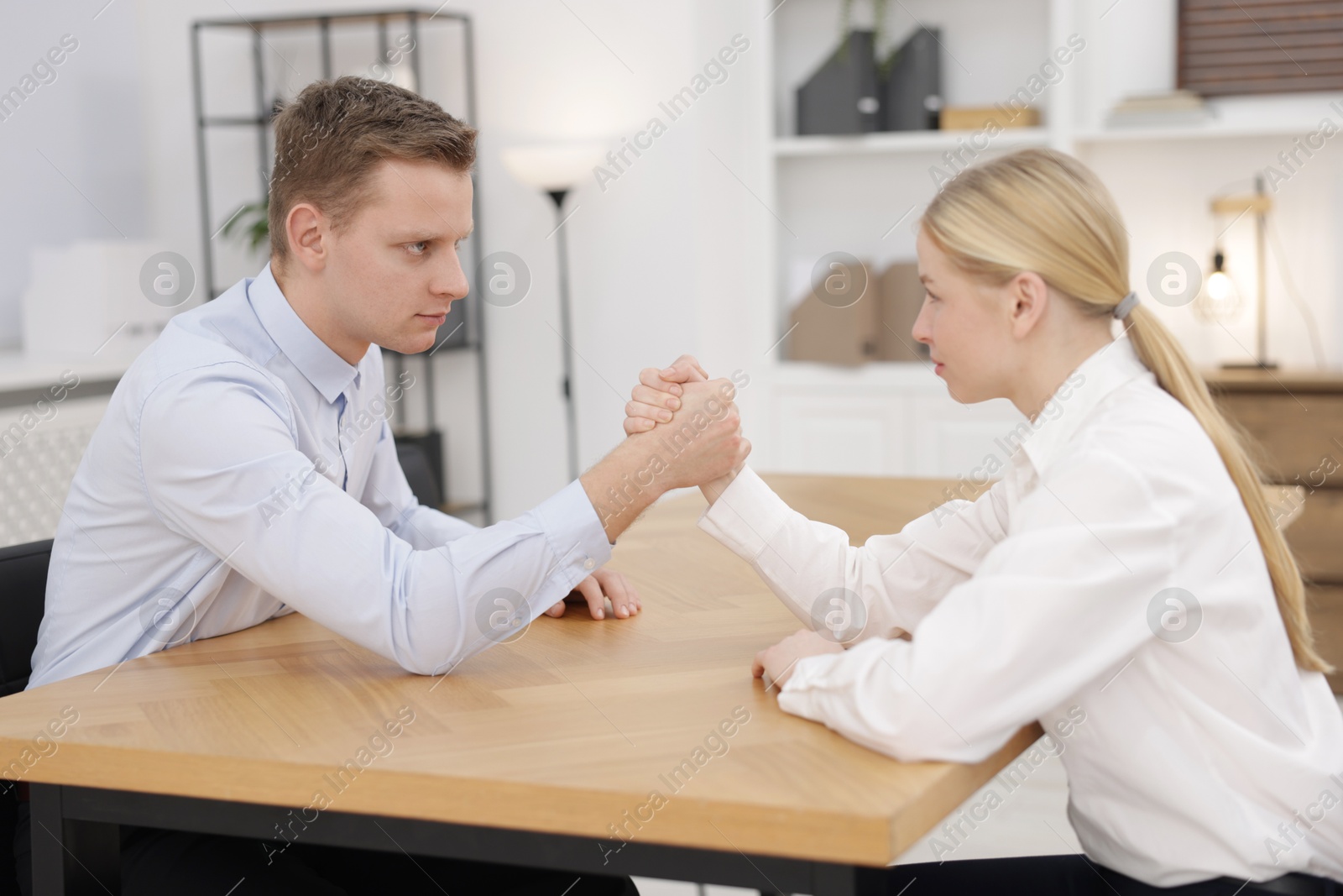 Photo of Competition concept. Businesspeople arm wrestling at table in office