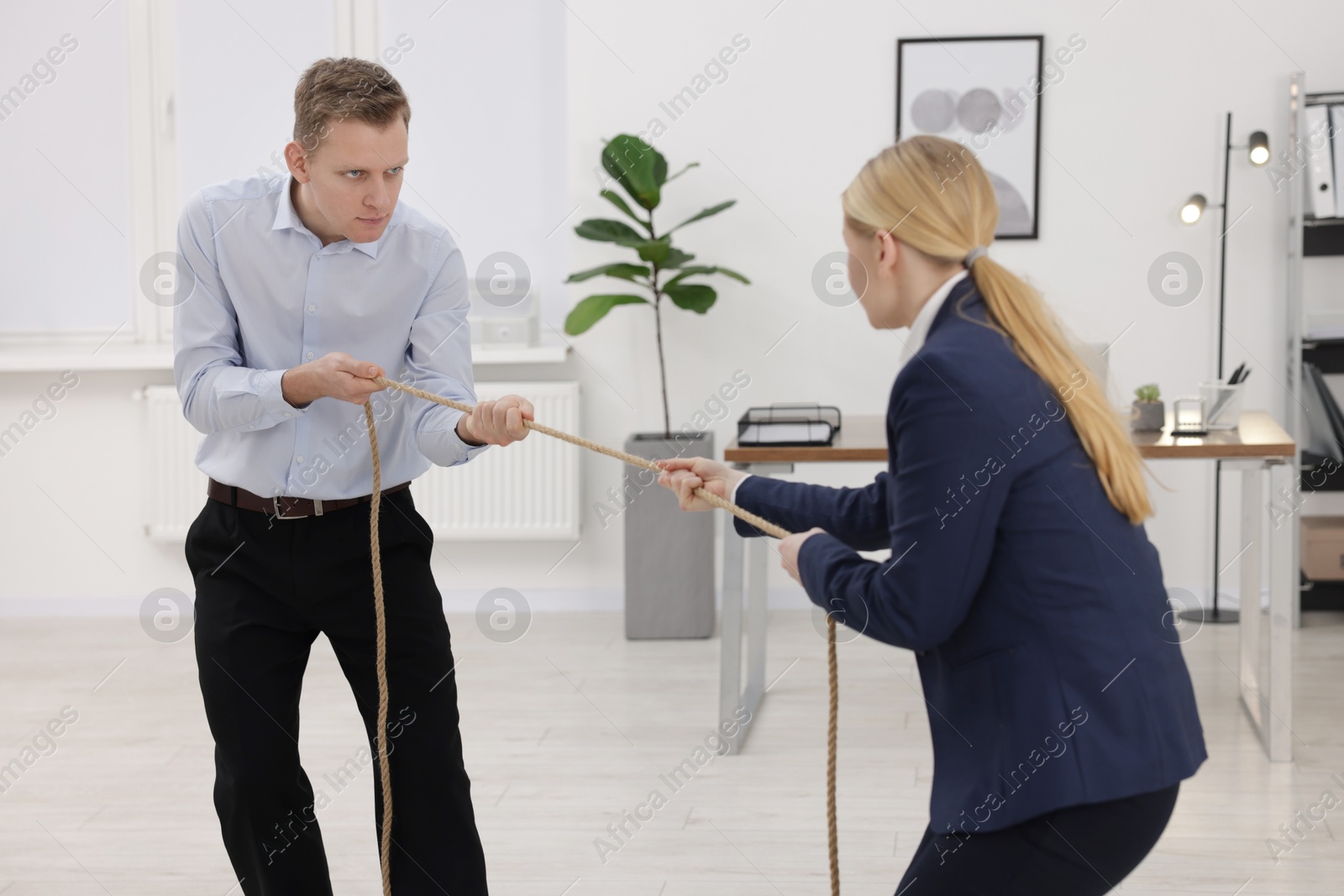 Photo of Competition concept. Businesspeople pulling rope in office