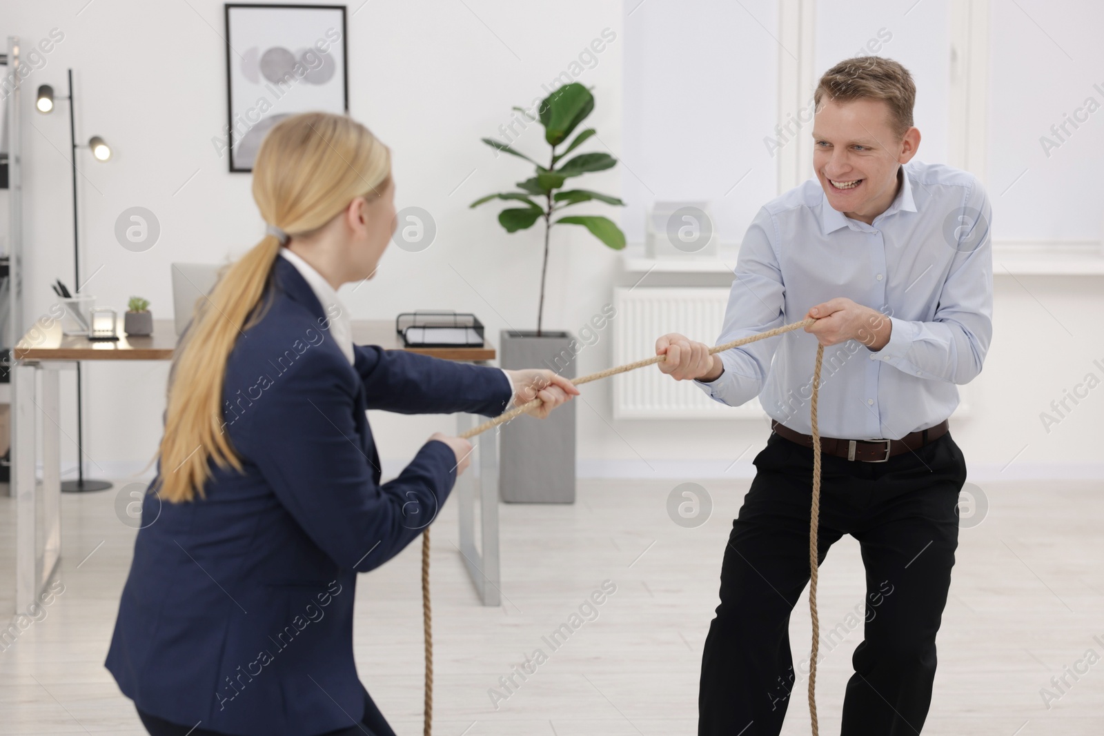 Photo of Competition concept. Businesspeople pulling rope in office