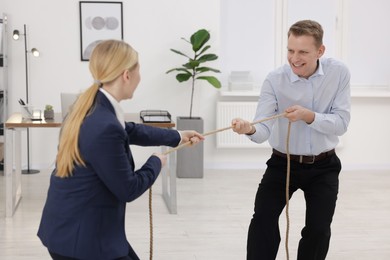 Competition concept. Businesspeople pulling rope in office