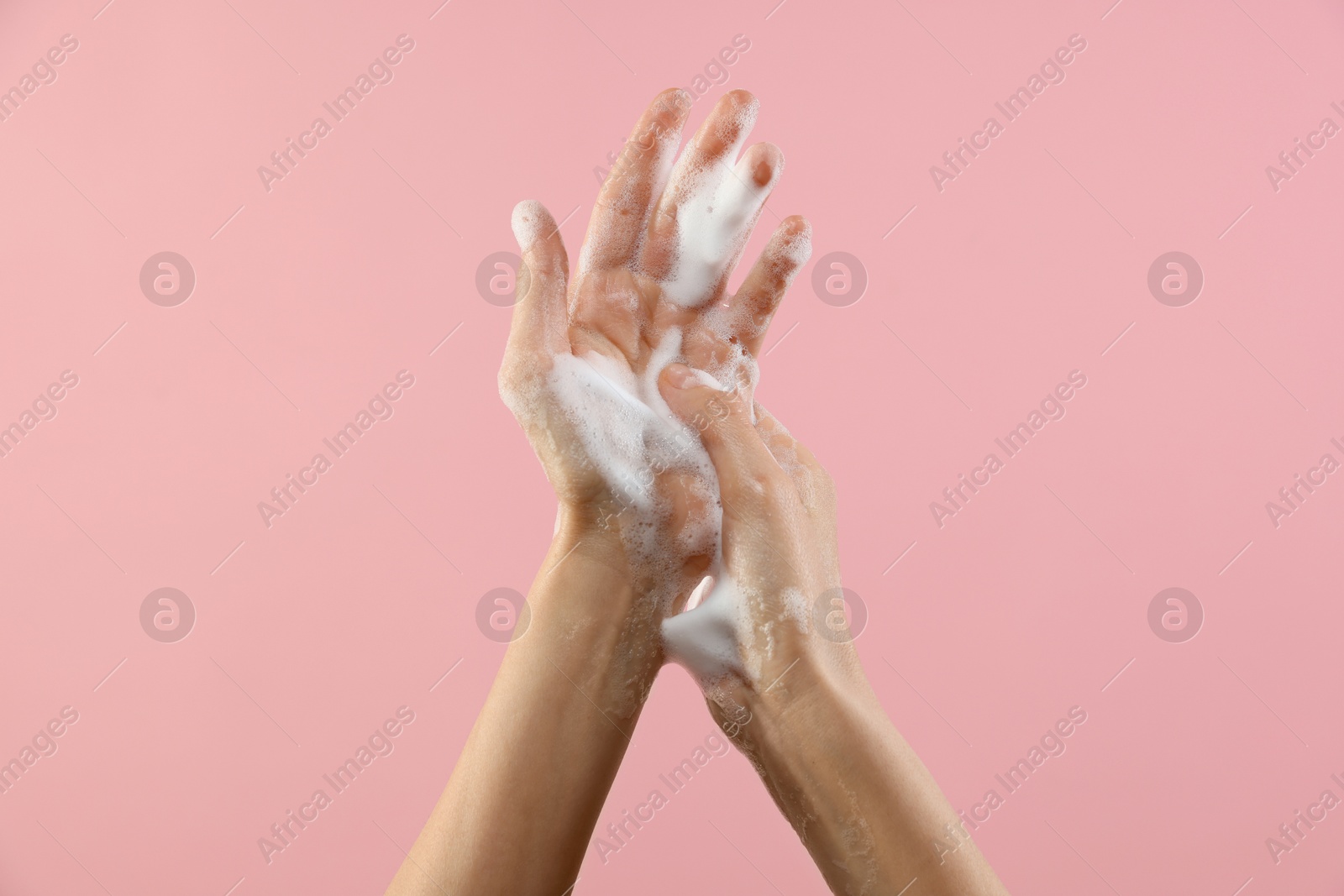 Photo of Woman washing hands with foaming soap on pink background, closeup. Hygiene