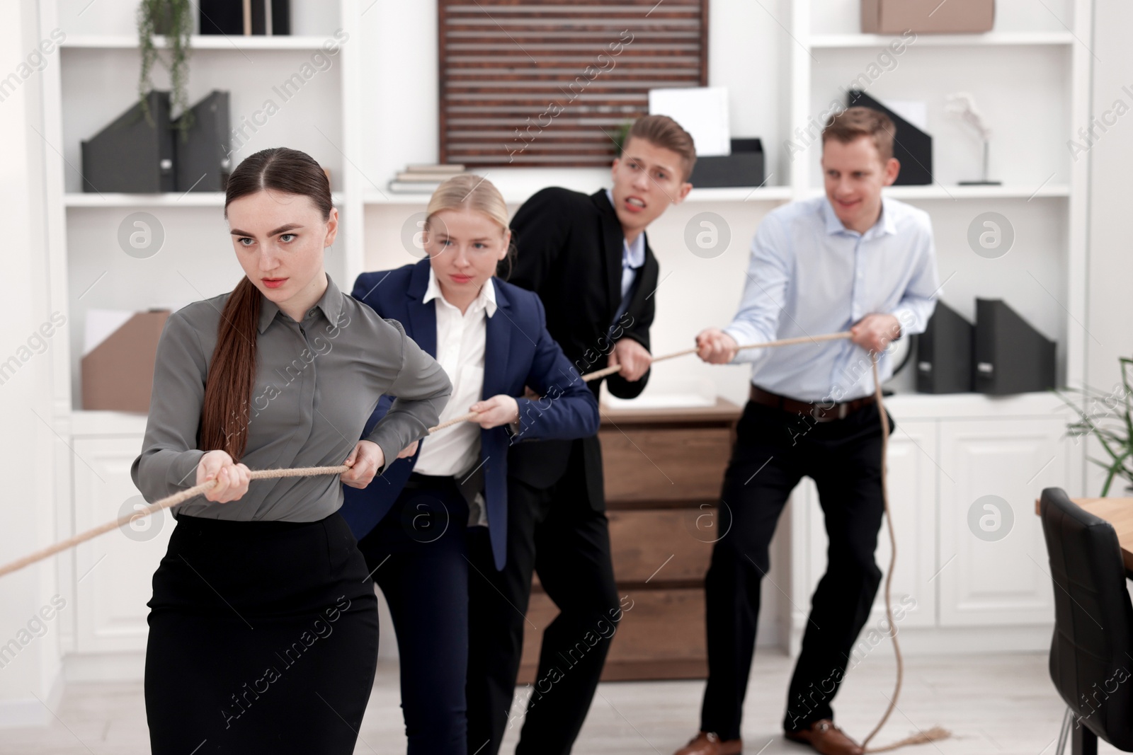 Photo of Competition concept. Group of businesspeople pulling rope in office