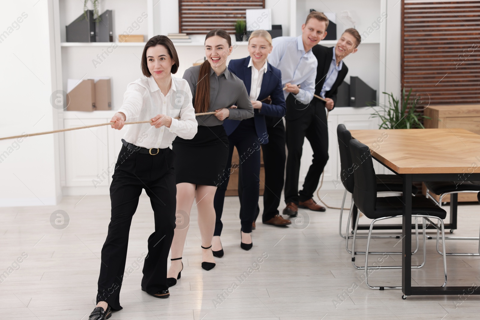 Photo of Competition concept. Group of businesspeople pulling rope in office