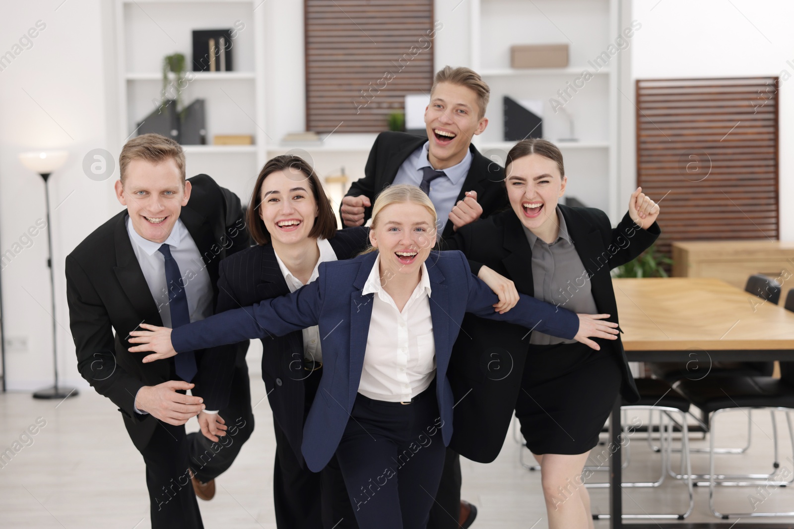 Photo of Competition concept. Group of happy businesspeople running in office