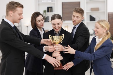 Competition concept. Group of businesspeople with golden trophy in office