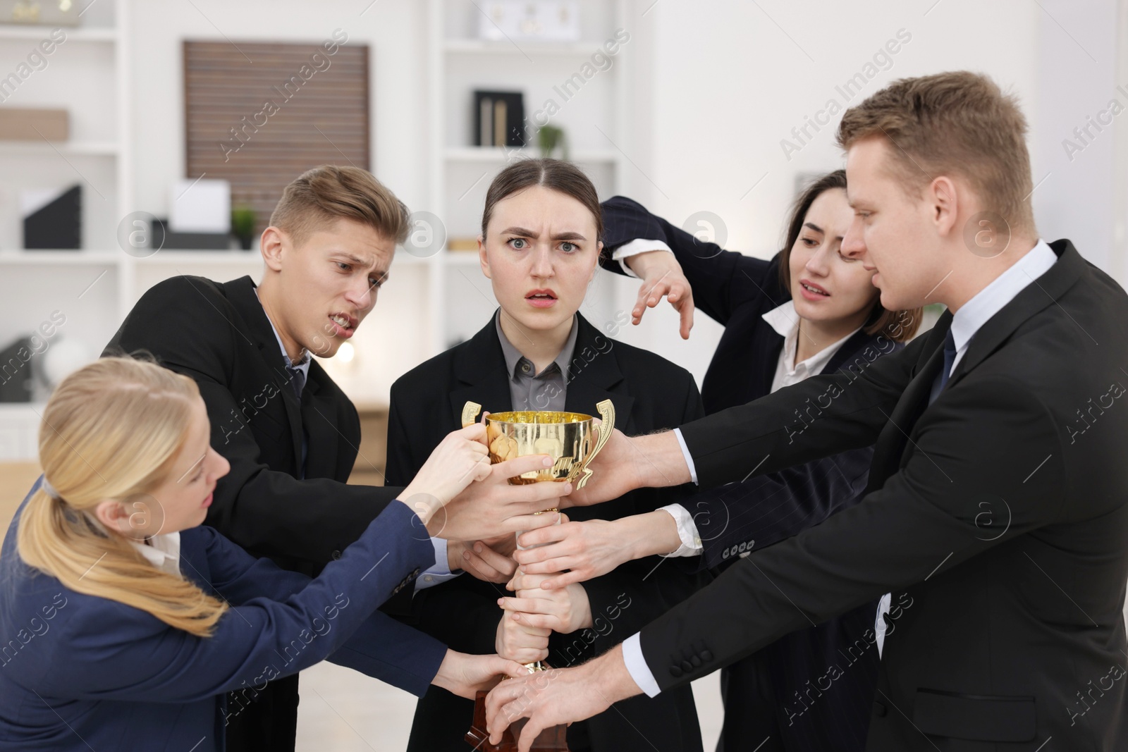 Photo of Competition concept. Group of businesspeople with golden trophy in office