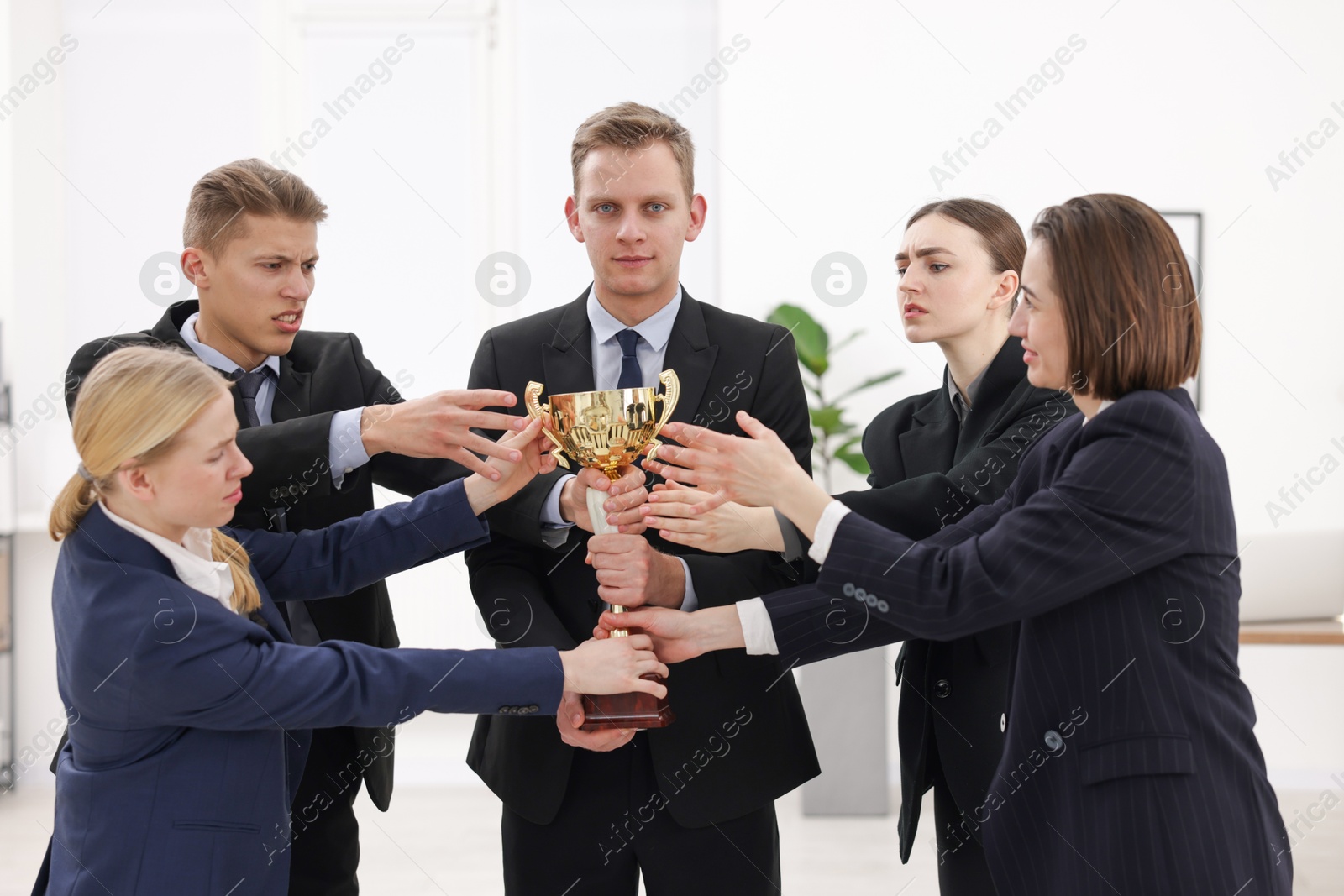 Photo of Competition concept. Group of businesspeople with golden trophy in office