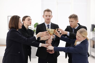 Competition concept. Group of businesspeople with golden trophy in office