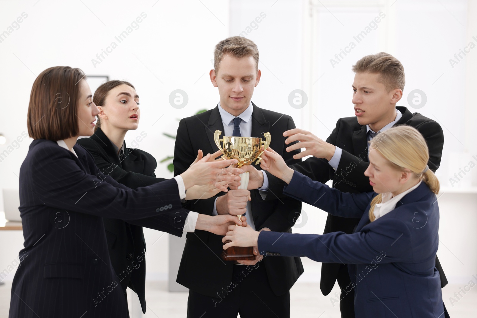 Photo of Competition concept. Group of businesspeople with golden trophy in office