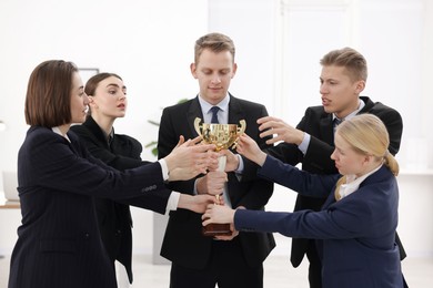 Competition concept. Group of businesspeople with golden trophy in office