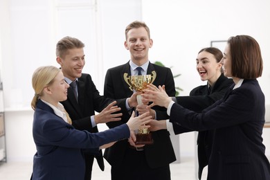 Competition concept. Group of businesspeople with golden trophy in office