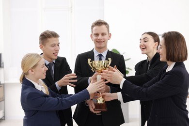 Photo of Competition concept. Group of businesspeople with golden trophy in office