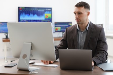 Financial trading specialist working on computer and laptop in office