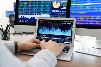 Photo of Financial trading specialist working on laptop at table in office, closeup