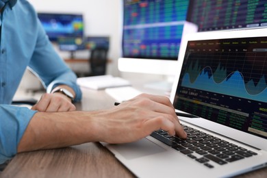 Photo of Financial trading specialist working on laptop at table in office, closeup