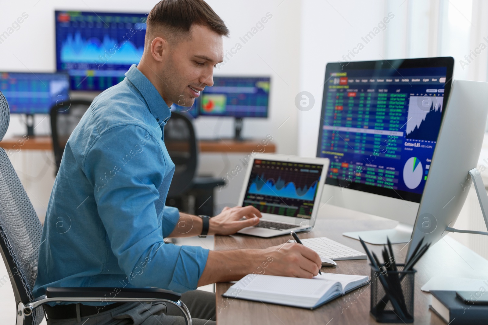 Photo of Financial trading specialist writing notes at table in office