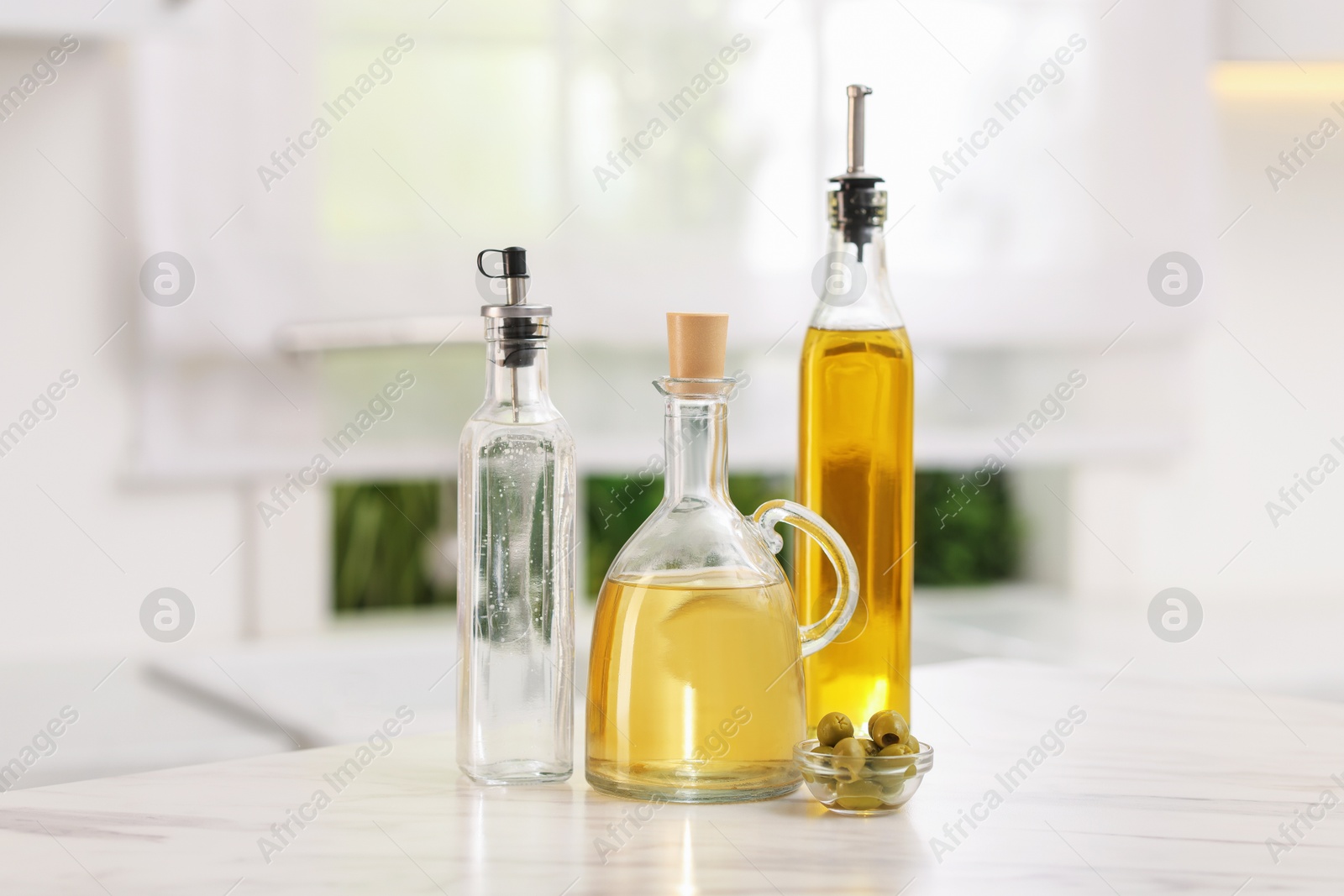 Photo of Salad dressings and olives on table in kitchen