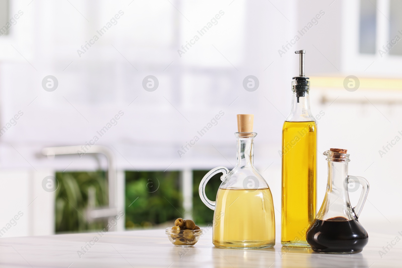 Photo of Salad dressings and olives on table in kitchen. Space for text