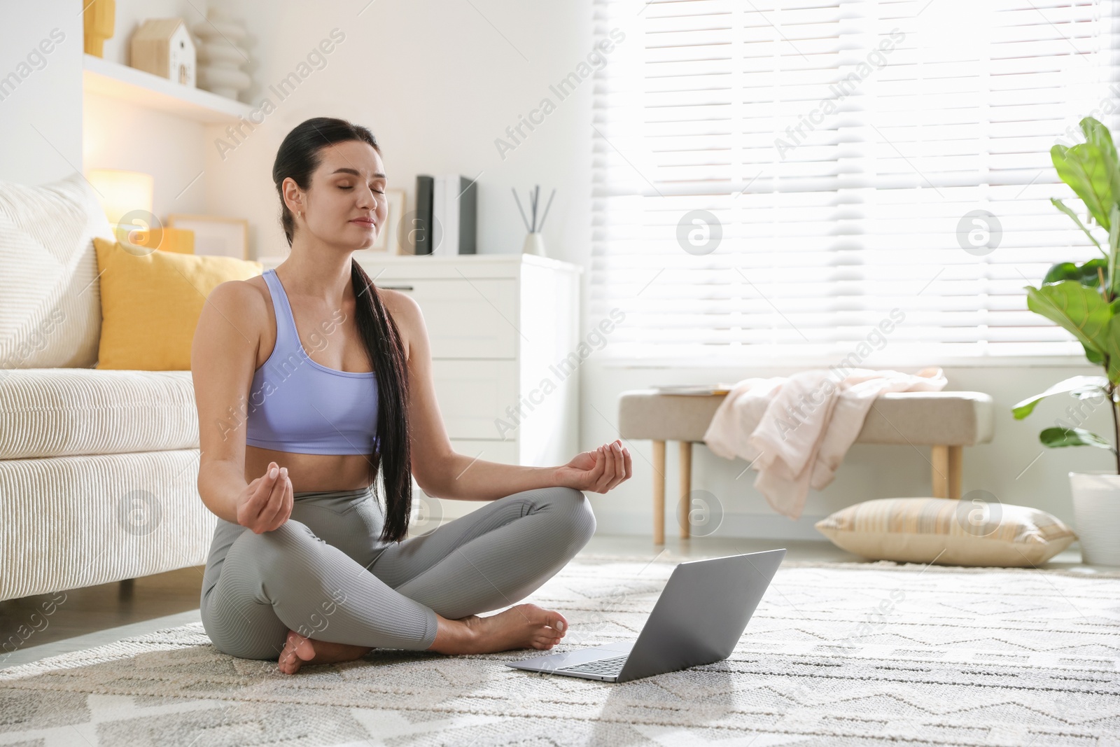 Photo of Woman with laptop meditating on floor at home. Space for text