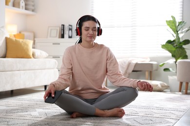 Photo of Woman with smartphone meditating on floor at home