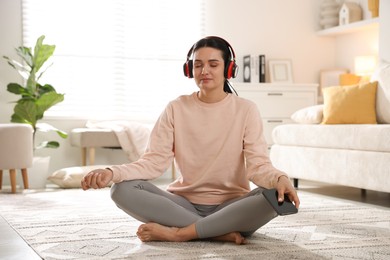 Woman with smartphone meditating on floor at home